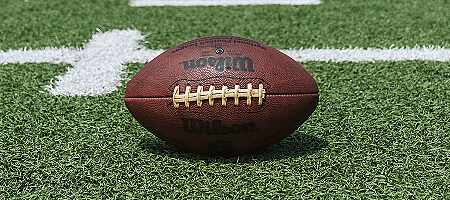 Nahaufnahme eines American Footballs auf dem grünen Rasen eines Spielfelds.