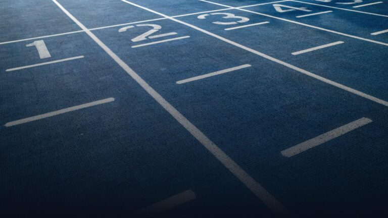Nummerierte Bahnen einer blauen Leichtathletik-Laufbahn in Nahaufnahme.
