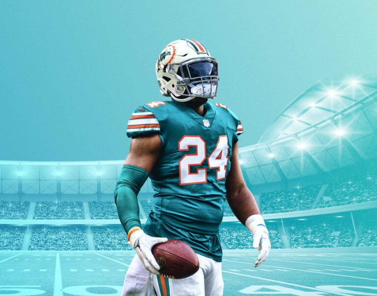 American-Football-Spieler im türkisfarbenen Trikot mit der Nummer 24, mit Ball im Arm in einem beleuchteten Stadion.